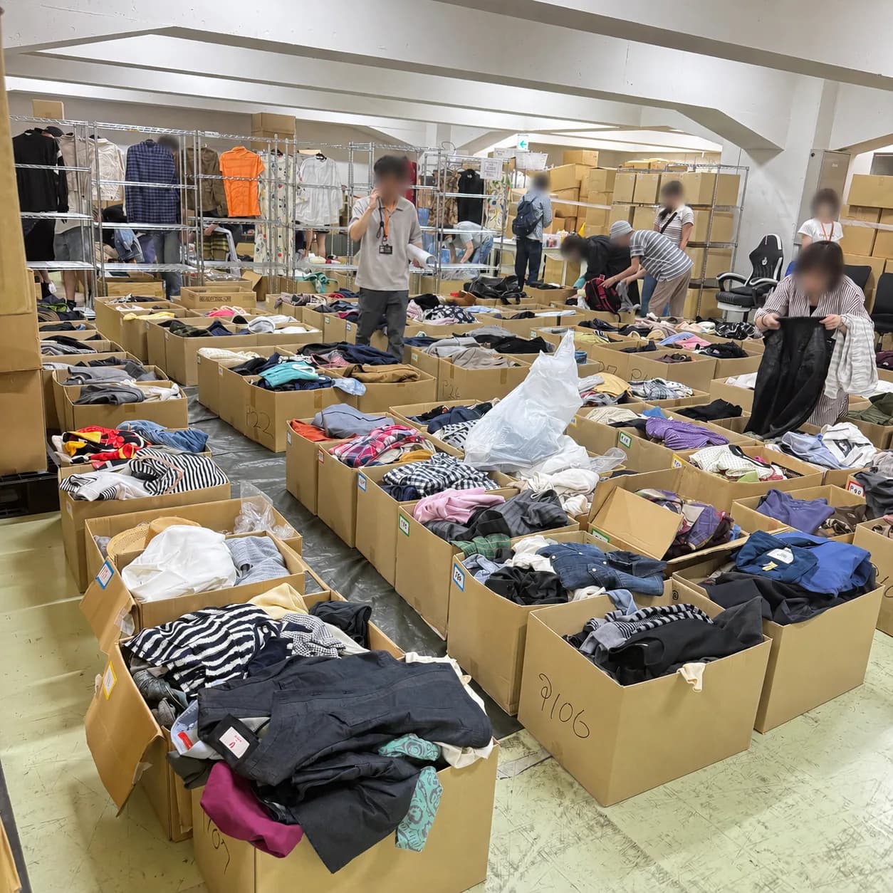 マカセルフリマ会場。段ボール箱に入った大量の中古アパレルを参加者が仕入れている様子